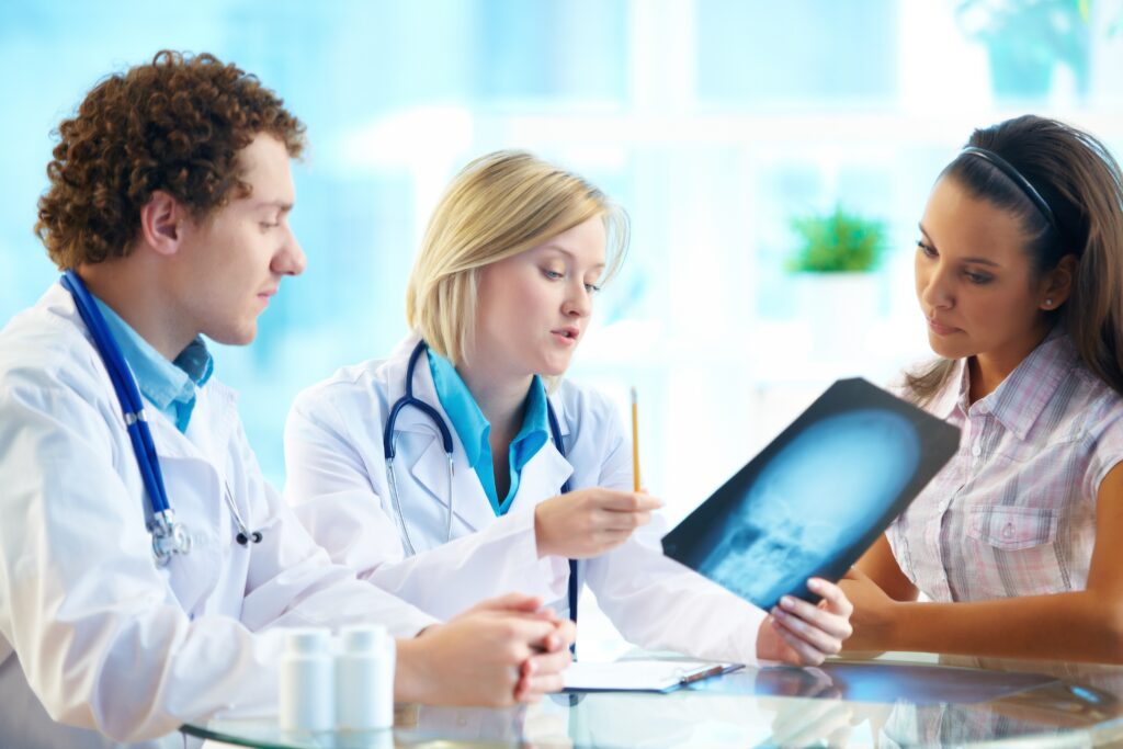 two doctors and young female patient reading cancer x-ray in hospital