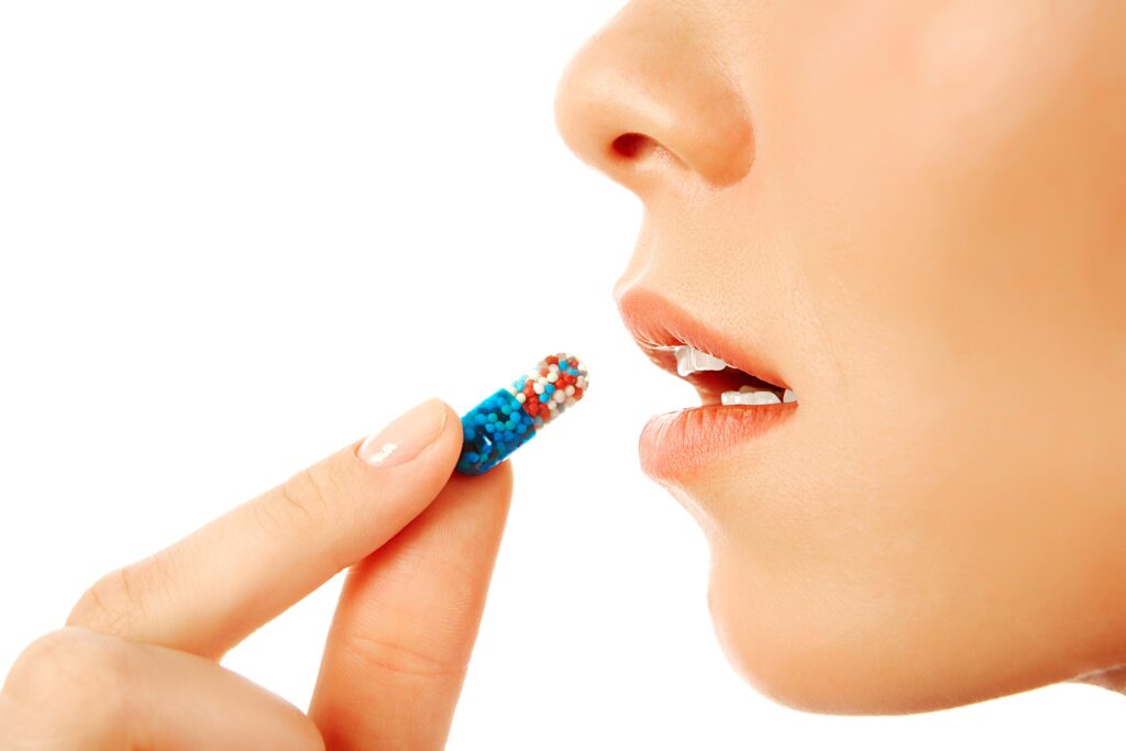 young woman holding treatment pill by her mouth
