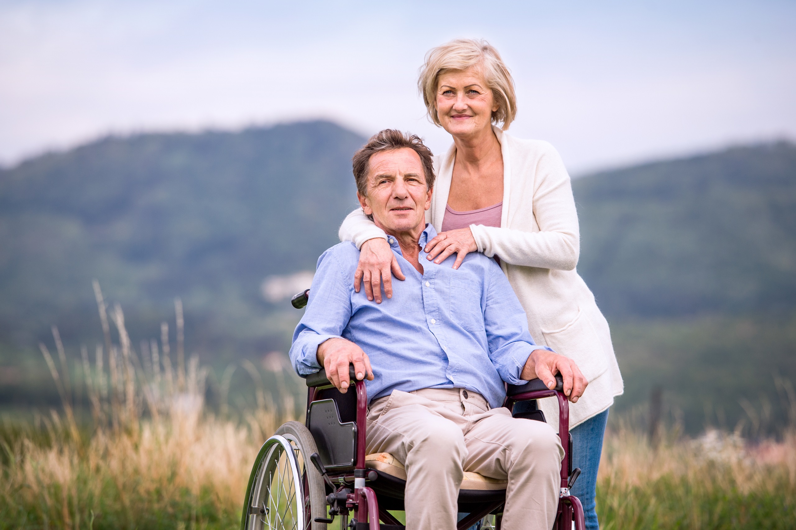 Senior woman pushing man in wheelchair health issues